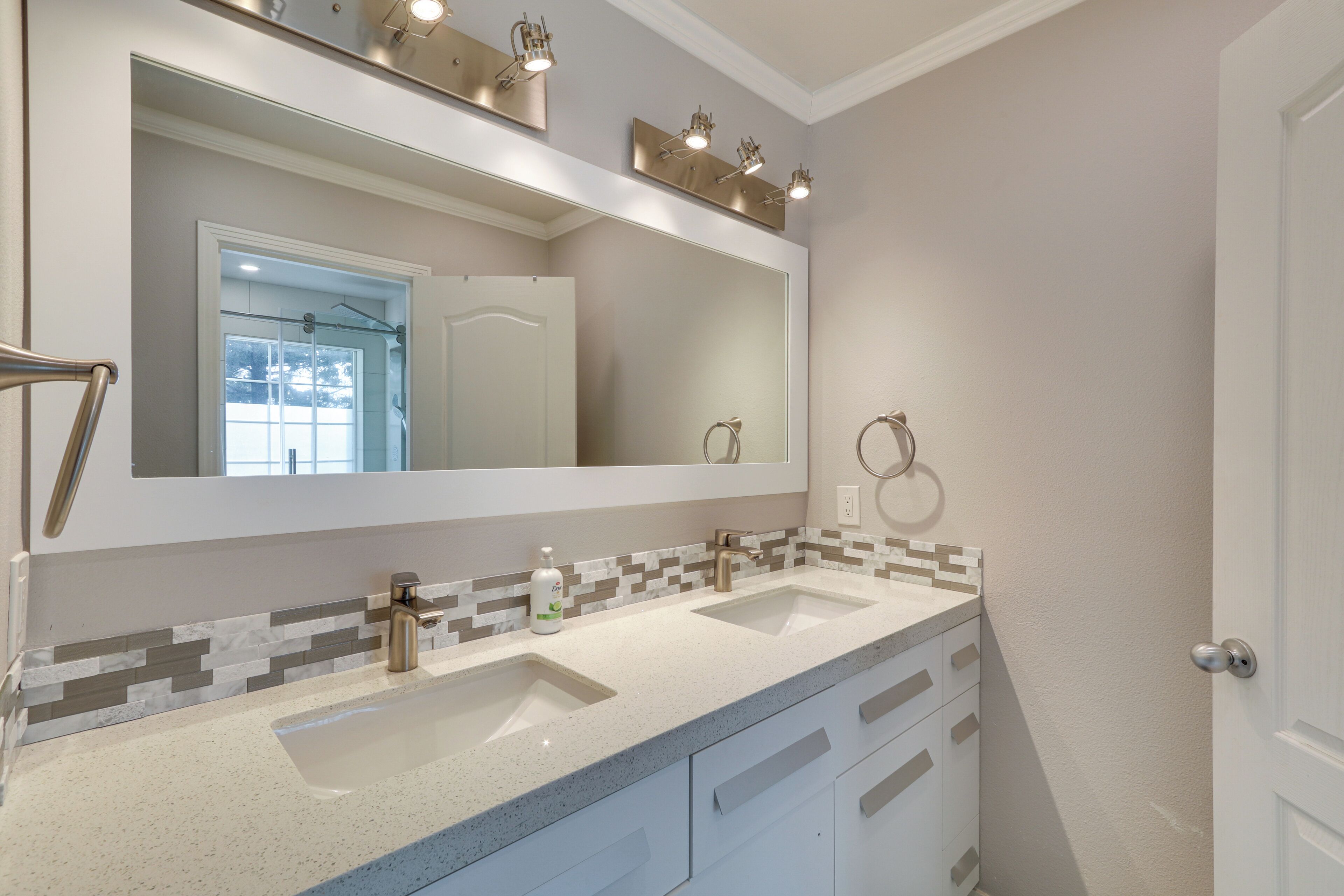 A bathroom with two sinks, a large mirror, and a towel rack.