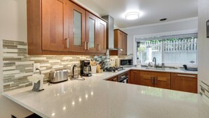 Una cocina con armarios de madera, un microondas y una ventana con vistas a la vegetación.