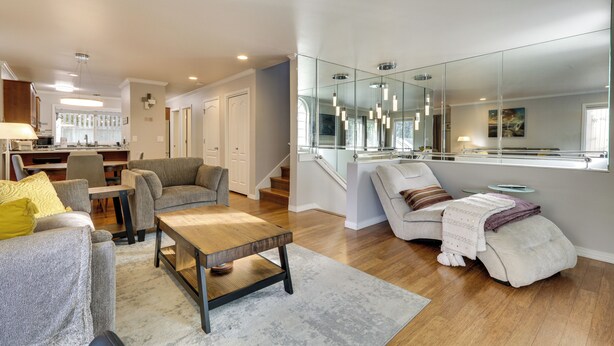Una sala de estar moderna con un sofá, un sillón y una mesa de centro. Se ve una escalera que sube a un nivel superior.