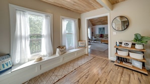 A room with large windows, a wooden ceiling, a built-in bench with storage, a mirror, and a shelf with decorative items. - Waterfront Home: Allegheny River Access, Dock Slip (Ford City)