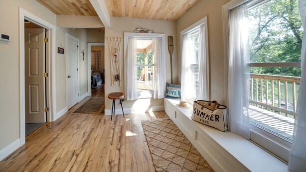 A hallway with wooden flooring, a bench, and a window with a view of a balcony. - Waterfront Home: Allegheny River Access, Dock Slip (Ford City)