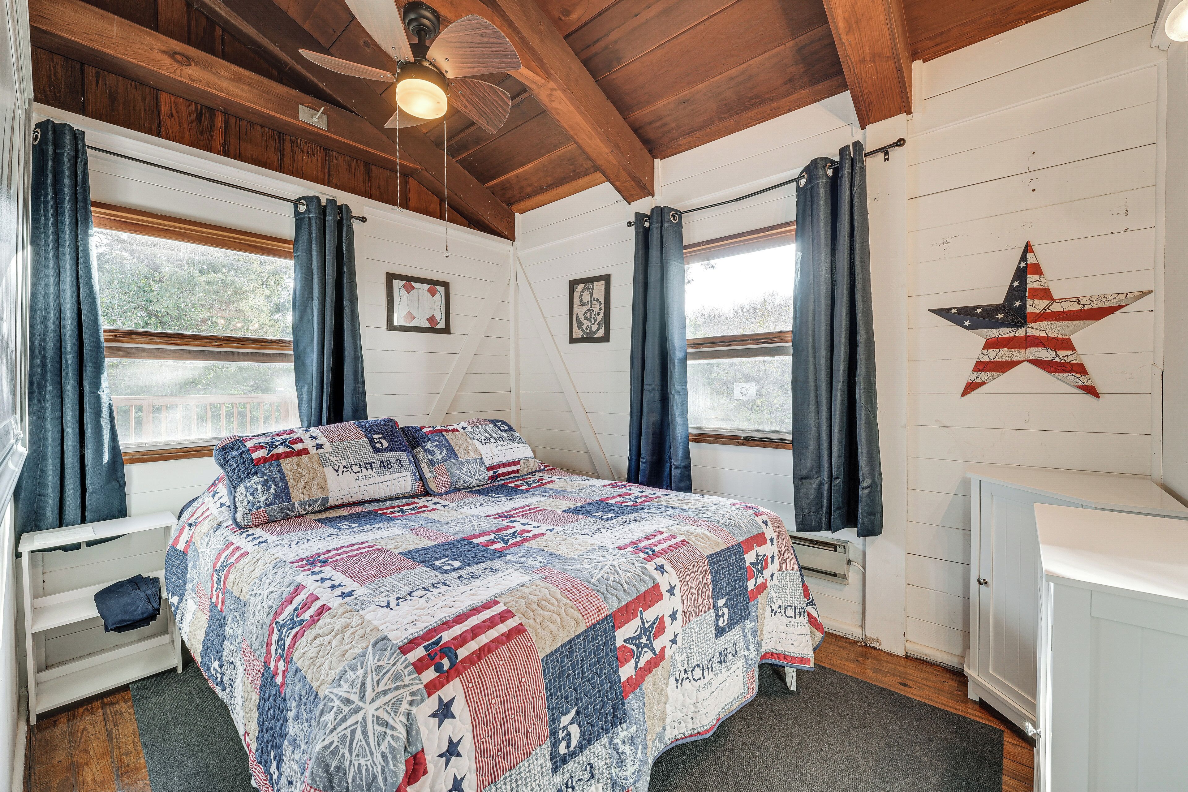 Une chambre avec un grand lit, des poutres en bois, un ventilateur de plafond et une décoration en forme d’étoile sur le mur.
