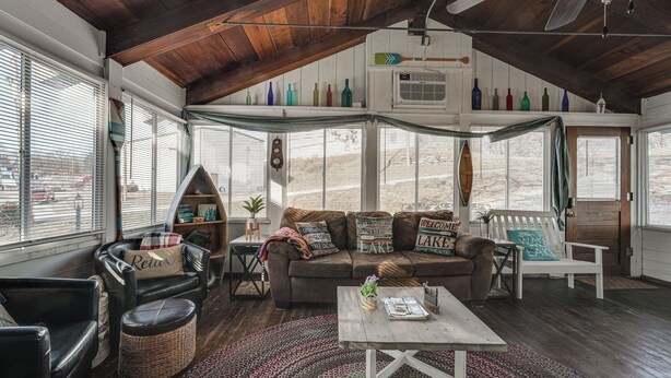 Ein gemütliches Wohnzimmer mit Holzbalkendecke, einem braunen Ledersofa, einem weißen Sessel und einem Couchtisch.