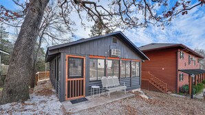 Eine Holzhütte mit überdachter Veranda, einer Bank und einem Tisch.
