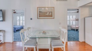 A dining area with a glass-top table, white chairs, and a framed picture on the wall. - Walk to Beach: Home w/ Pool Access in Myrtle Beach (Myrtle Beach)