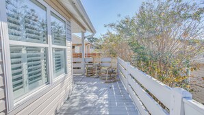 A wooden deck with a white railing, large windows, and a view of trees. - Walk to Beach: Home w/ Pool Access in Myrtle Beach (Myrtle Beach)