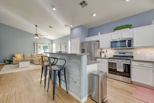A modern kitchen with white cabinets, stainless steel appliances, and a wooden island with bar stools.