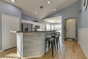 A modern kitchen with a central island, white cabinetry, and a stainless steel refrigerator.