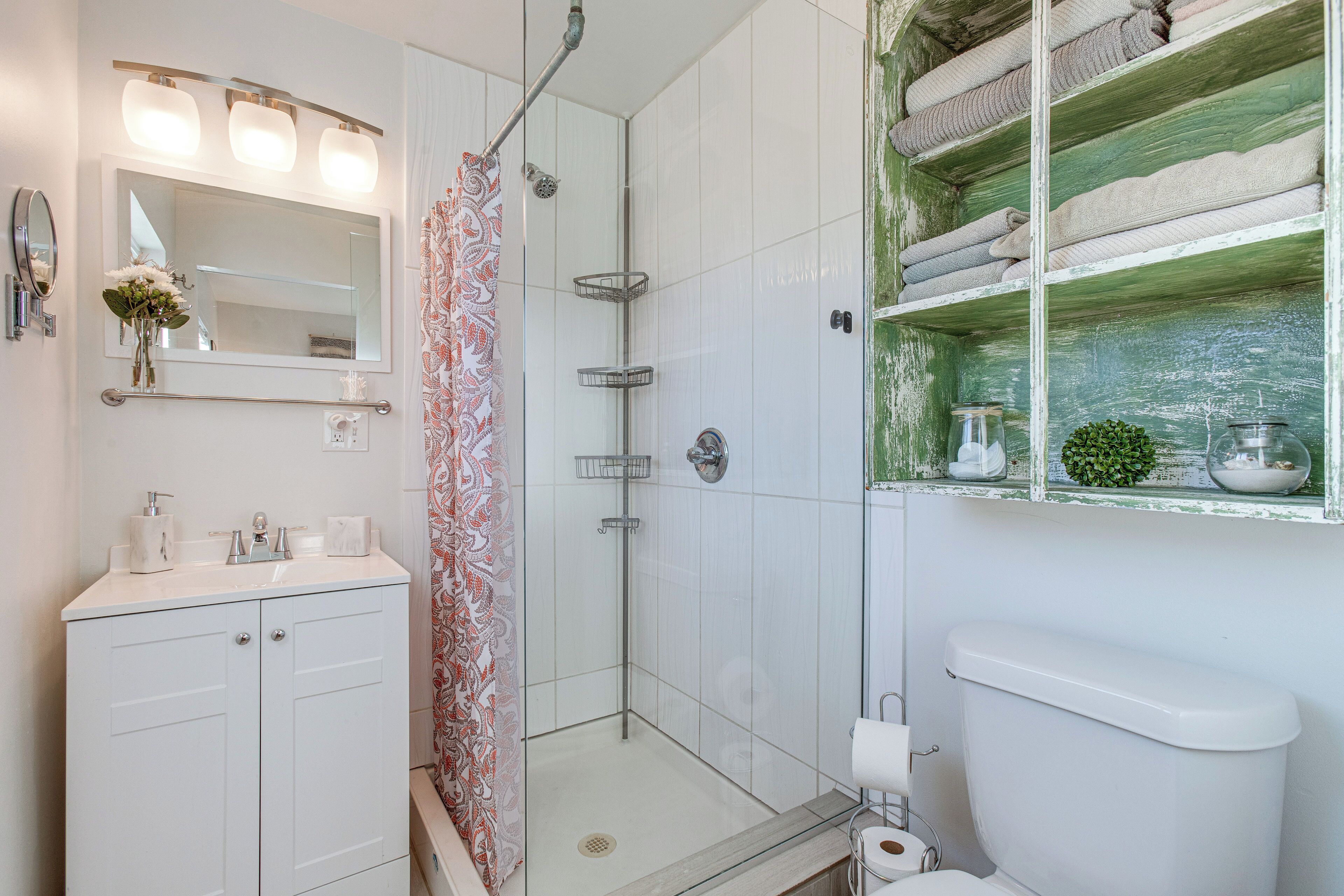 Ein Badezimmer mit Dusche, Toilette und Waschtisch mit Spiegel und Handtuchhalter.