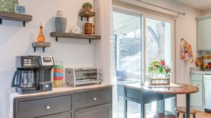 Ett kök med en kaffebryggare, en brödrost och diverse dekorativa föremål på hyllorna.