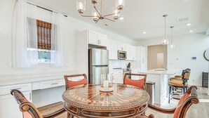 A modern kitchen with white cabinets, a stainless steel refrigerator, and a round dining table with chairs. - Charming Charlotte Townhome: 6 Mi to Downtown! (Charlotte)