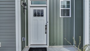 A front door with a small window above it, a mailbox, and a welcome mat. - Charming Charlotte Townhome: 6 Mi to Downtown! (Charlotte)