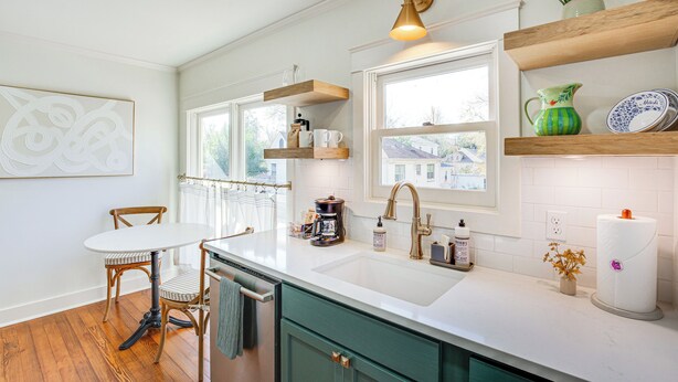 A kitchen with a white countertop, wooden cabinets, a sink, and a dining area with a table and chairs. - 2 Mi to Tyler Rose Garden: Vibrant Apartment! (Tyler)