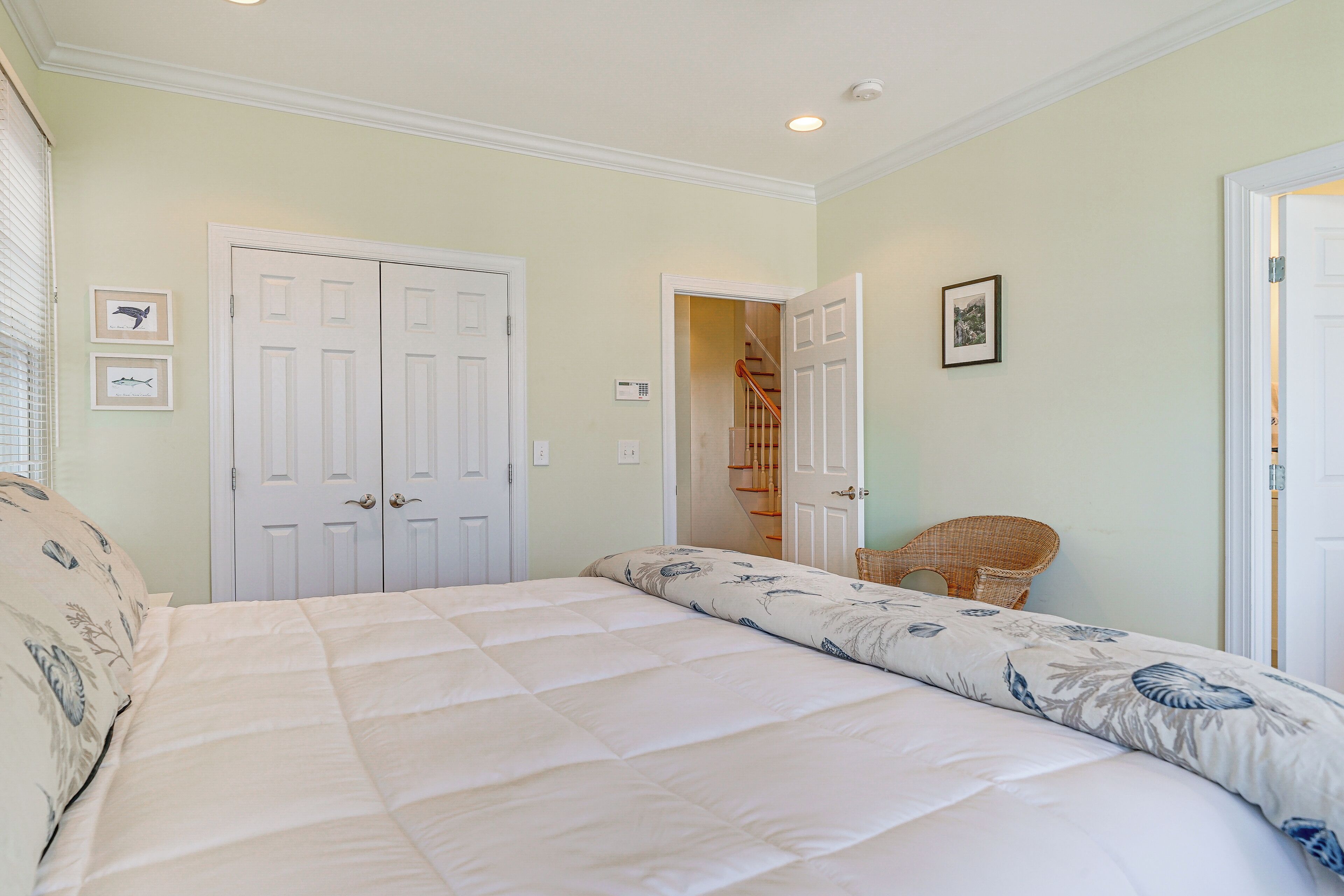 A bedroom with a bed, two doors, a chair, and a staircase.