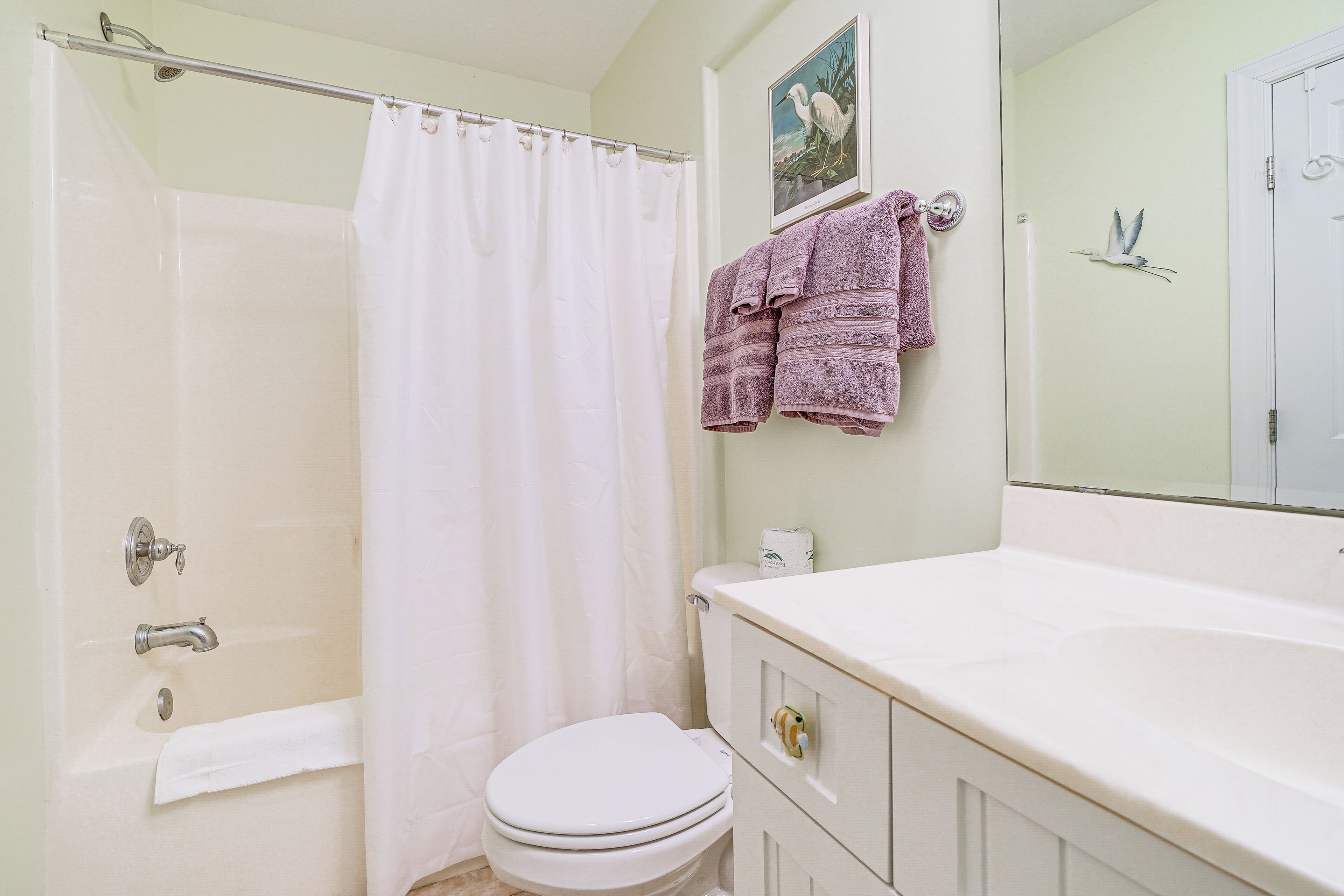 A bathroom with a bathtub, toilet, and a vanity with a mirror.