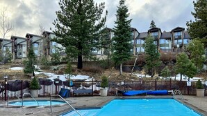 A swimming pool with a diving board and a slide, surrounded by a fence and trees. - Ski-in/Ski-out with views at Sunstone (Mammoth Lakes)