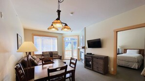 A dining area with a table and chairs, a lamp, and a television on the wall. - Ski-in/Ski-out with views at Sunstone (Mammoth Lakes)