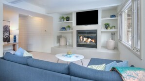 A modern living room with a large blue sofa, a white coffee table, and a fireplace with a flat-screen TV above it. - Private East Vail Home on Bus Rte, 5187GC (Vail)