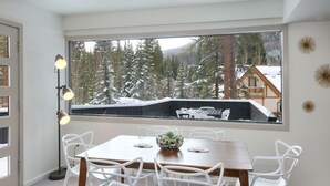 A dining area with a large window, white chairs, a wooden table, and a floor lamp. - Private East Vail Home on Bus Rte, 5187GC (Vail)