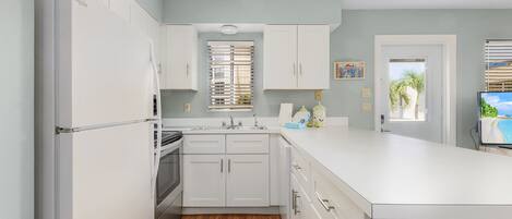 A modern kitchen with white cabinets, a built-in oven, and a large island with a sink.
