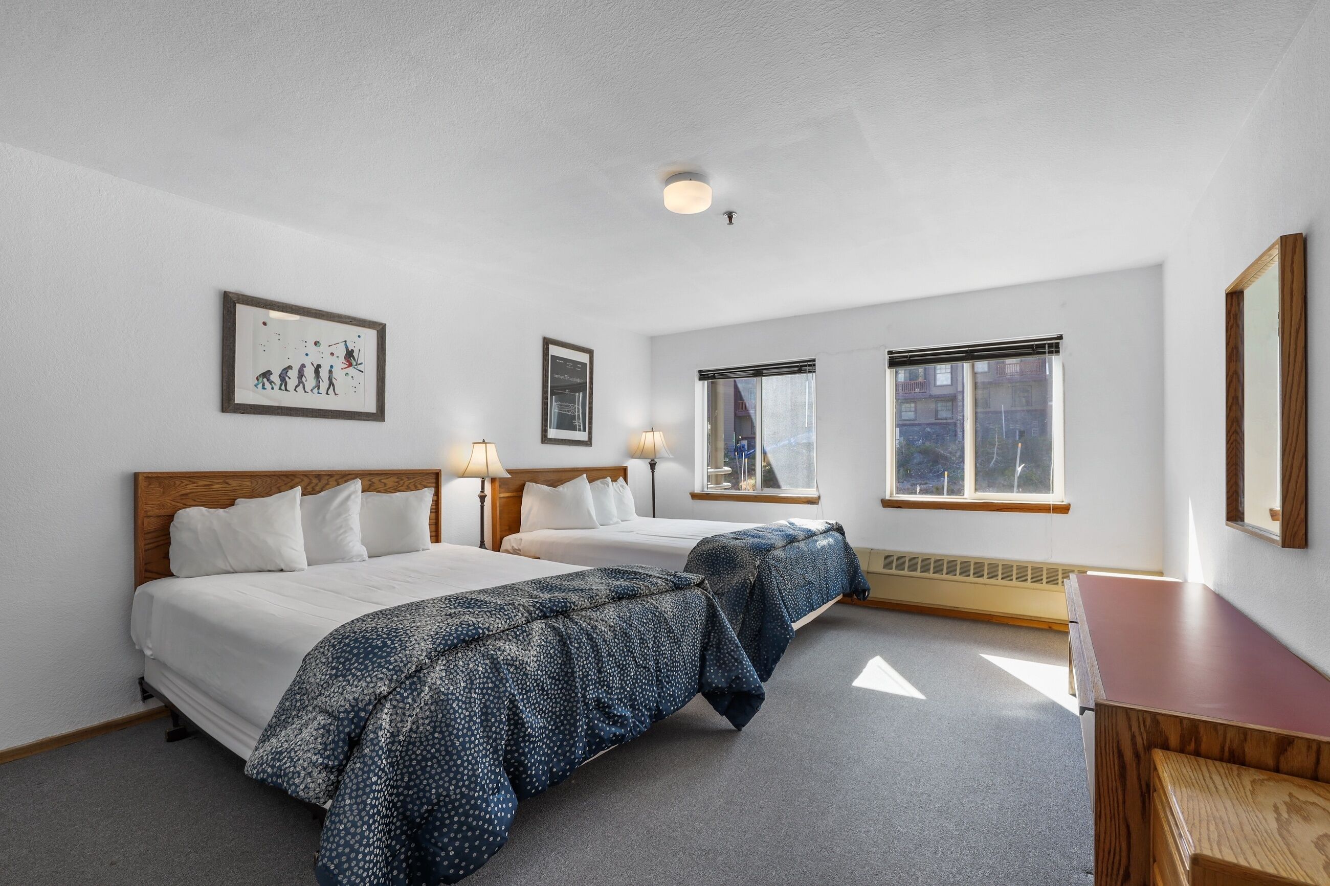 Habitación de hotel con dos camas, cabecero de madera, escritorio y ventana con persianas.