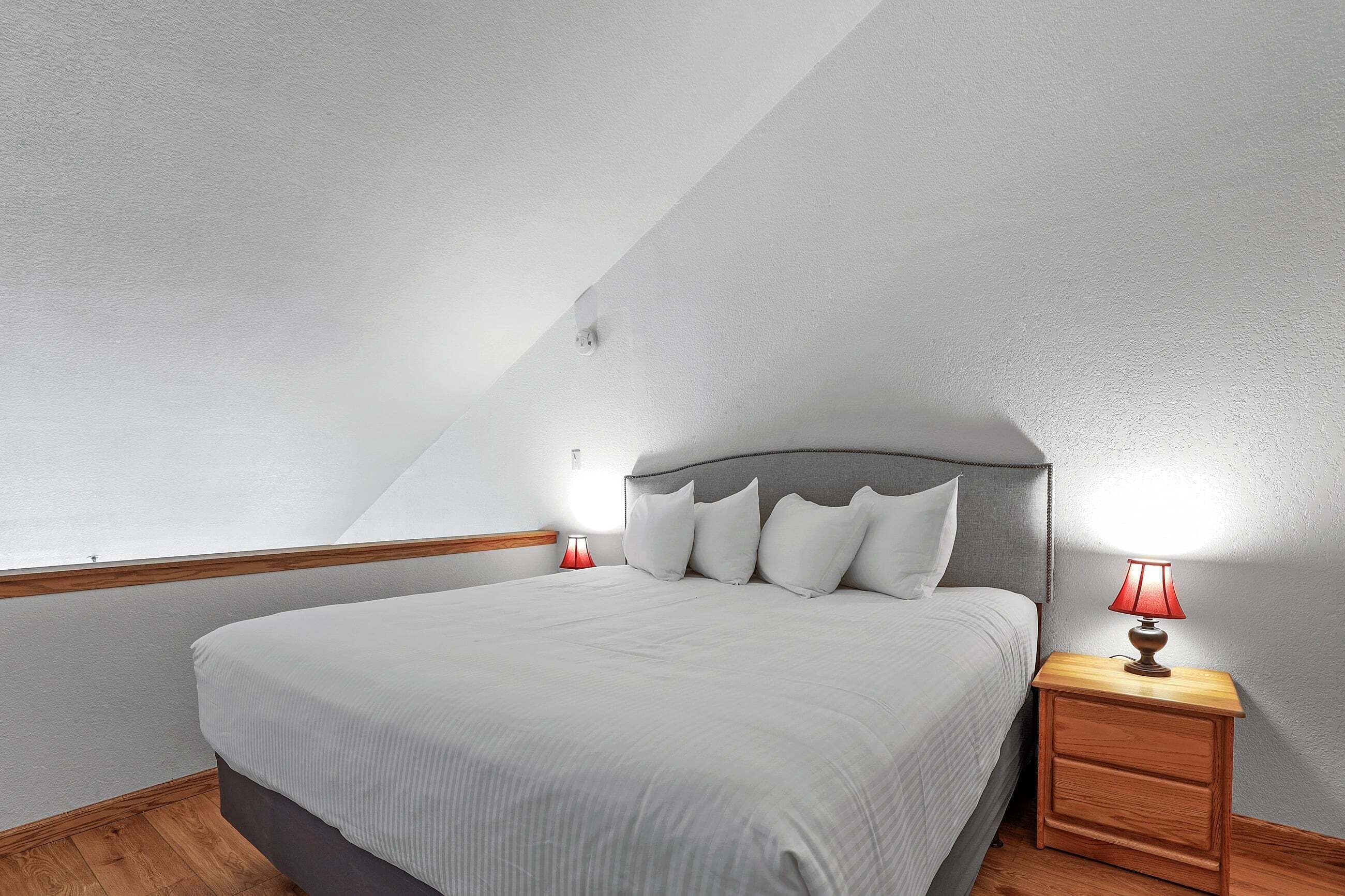 Une chambre à coucher avec un lit, une table de chevet avec une lampe et une fenêtre.