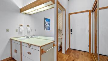 Un baño con tocador de madera, espejo, lavamanos e inodoro.