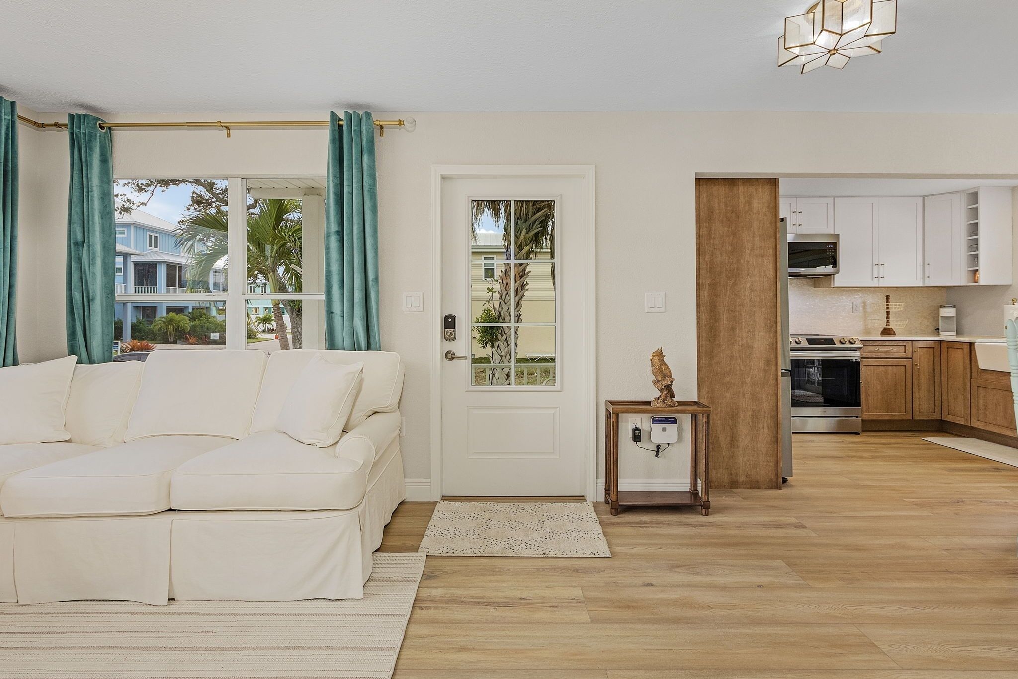 A living room with a sofa, a door, and a view of the outside.