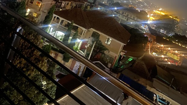 Ein Nachtblick auf eine Stadtlandschaft mit Gebäuden, einer Straße und einer entfernten Hügelkette.