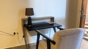 Ein kleiner, kompakter Arbeitsbereich mit Schreibtisch, Stuhl und Lampe.