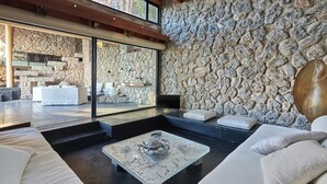 A modern interior with stone walls, a glass door leading outside, and a seating area with a coffee table. - Cala Piccola, Monte Argentario, Grosseto and Maremma (Monte Argentario)
