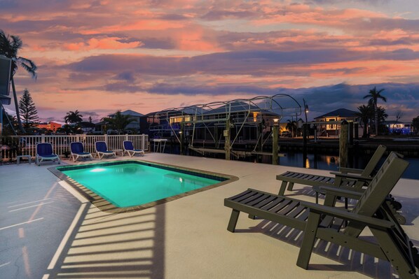 A pool area with lounge chairs, a wooden deck, and a view of a dock and water. - ☀️Private, Heated Pool-Canal Front with Beautiful Views-Drift Inn☀️ (Fort Myers Beach)