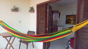 A hammock in a room with a tiled floor, a wooden door, and a painting on the wall. - Pousada & SPA Barra do Mundaú (Trairi)