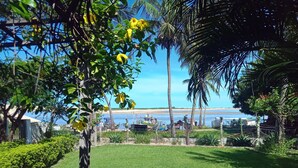 A well-maintained grassy area with a clear view of the beach and ocean in the background. - Pousada & SPA Barra do Mundaú (Trairi)
