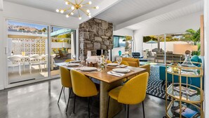 Un espace de restauration moderne avec une table en bois, des chaises jaunes et un mur en pierre.