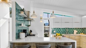 Une cuisine moderne dotée d’un grand îlot central, de tabourets de bar et offrant une vue sur les montagnes.