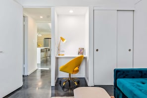 A modern room with a teal sofa, a yellow office chair, a desk with a lamp, and a white door. - Starburst PS - Vibrant Mid-Mod Escape (Palm Springs)