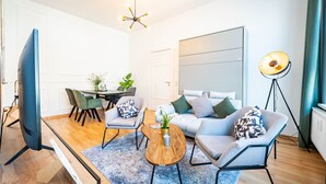 Una sala de estar moderna con un sofá, sillas, una mesa de centro y un televisor.