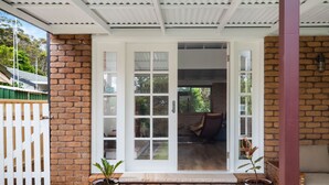 A covered porch with a brick wall, a white door with glass panels, and a bench inside. - 4 Shelly Beach Road: 2  BR, 2  BA House in Port Macquarie , Sleeps 4 (Port Macquarie)