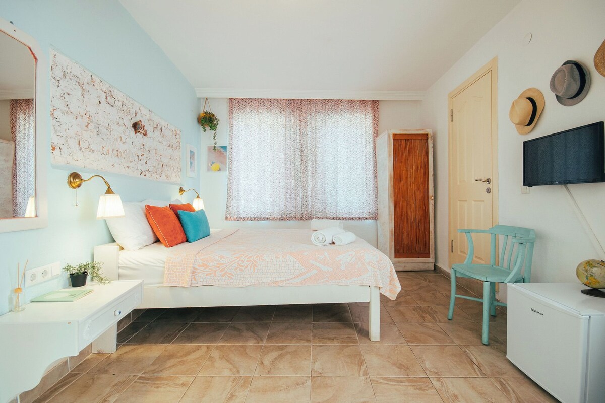 Une chambre à coucher comprenant un lit, des tables de chevet, une télévision, une armoire et une fenêtre avec des rideaux.