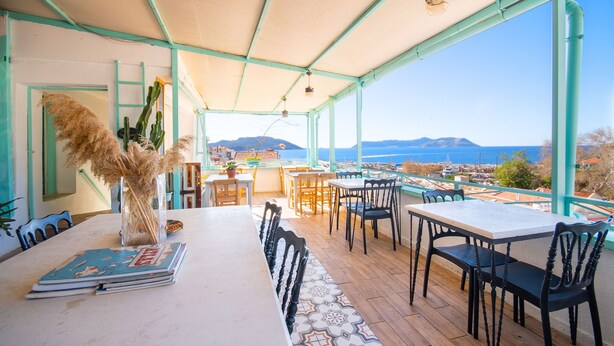 Un espace extérieur aménagé pour prendre les repas, offrant une vue sur la mer et les montagnes.