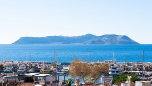 Un port de plaisance avec des bateaux amarrés, une vue dégagée sur la mer et une montagne en arrière-plan.