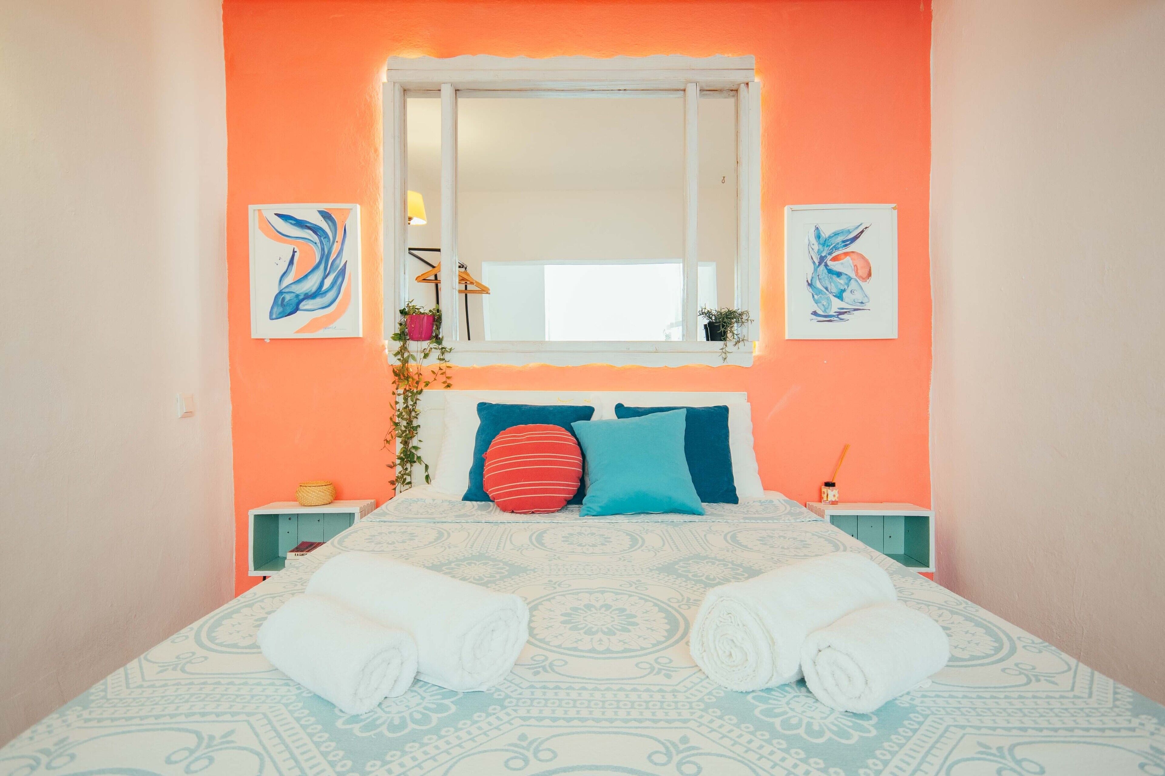 Una cama con una colcha estampada, dos almohadas y dos toallas enrolladas.
