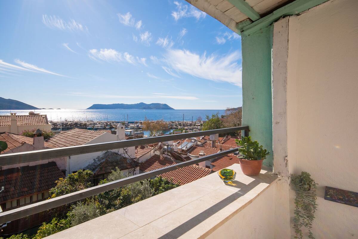 A balcony with a view of a marina and distant mountains.