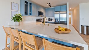 Eine moderne Küche mit blauen Schränken, einer großen Kochinsel und einem Edelstahl-Kühlschrank.
