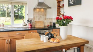 Una cocina con armarios de madera, encimera negra, estufa y ventana con vistas a un jardín.