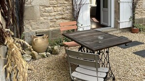 Een terras met een tafel en stoelen, een rustieke stenen muur en een houten bank.