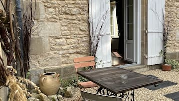 Un espace extérieur aménagé avec une table et des chaises, un mur en pierre rustique et un banc en bois.