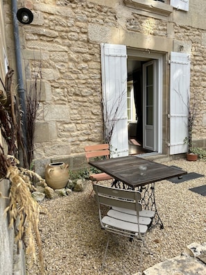 An outdoor seating area with a table and chairs, a rustic stone wall, and a wooden bench.