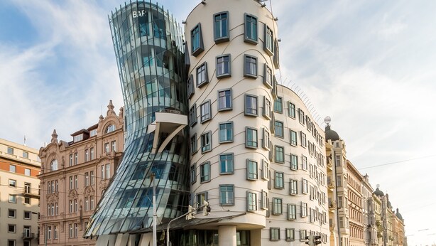 A building with a curved glass facade and a traditional multi-story structure with balconies. - Central Cozy & Charming Residence 3min from Riverside Prague (Hlavní mesto Praha)
